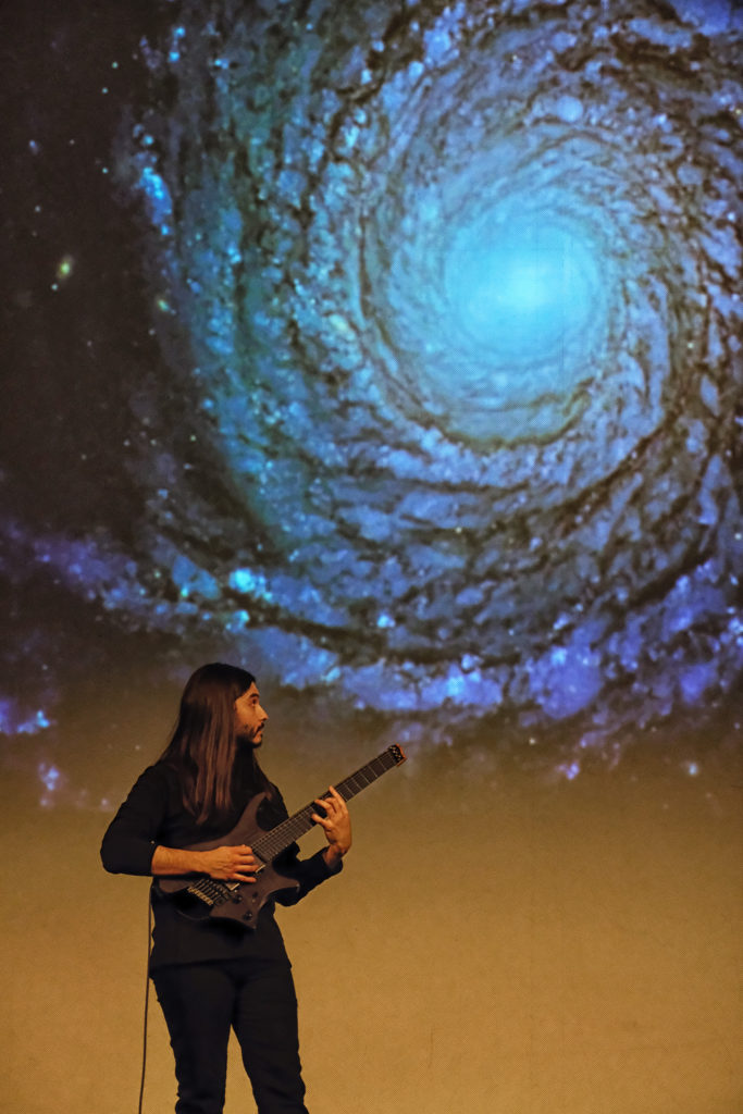 Álvaro Domene playing guitar, galaxy background